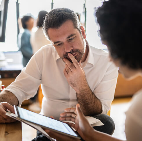 Mature man looking at a digital tablet that a colleague is showing at work